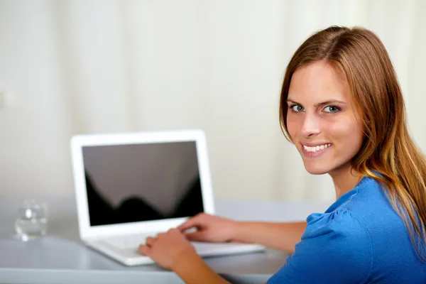Gülümseyen ve dizüstü bilgisayarınızda çalışan genç kadın — Stok fotoğraf