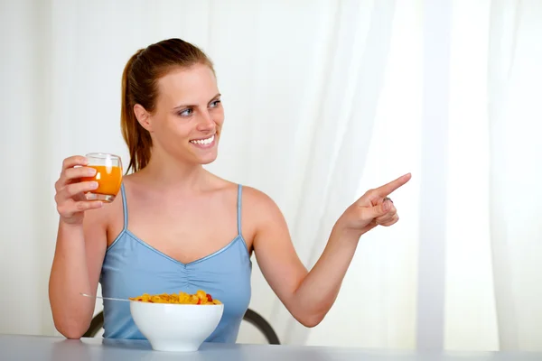 Mujer joven caucásica comiendo y señalando — Foto de Stock