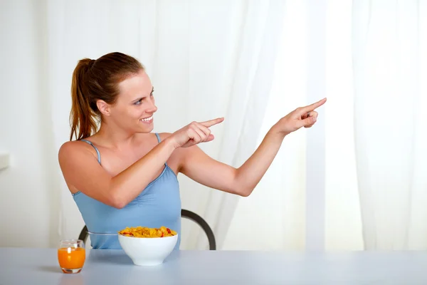 Charming youmg woman eating meal and pointing — Stock Photo, Image