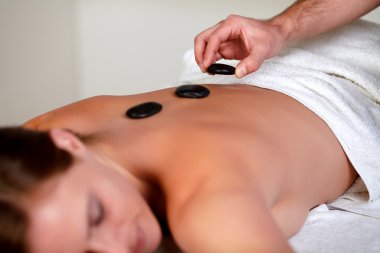 Young girl relaxing and having a hot stone massage clipart