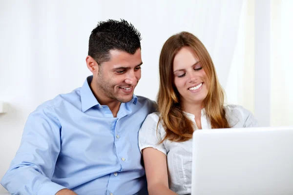 Casal amigável usando um laptop — Fotografia de Stock