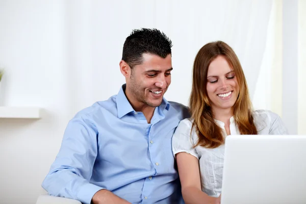 Веселая пара улыбается и пользуется ноутбуком — стоковое фото