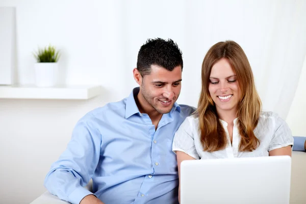 Молода пара посміхається і використовує ноутбук — стокове фото