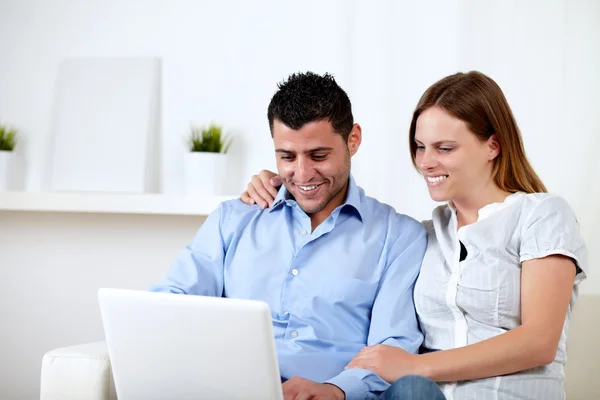 Attractive couple smiling and looking to computer — Stock Photo, Image