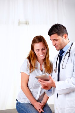 Handsome doctor and a patient looking to tablet PC clipart