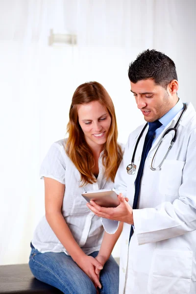 Latin läkare och en kvinna som ser för att tablet pc — Stockfoto