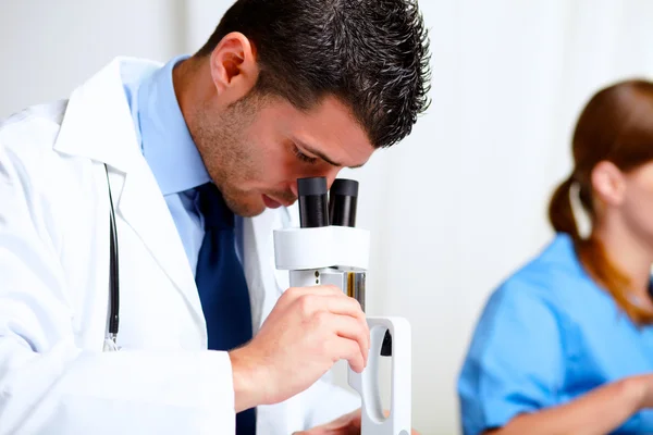 Atractivo médico latino usando un microscopio — Foto de Stock