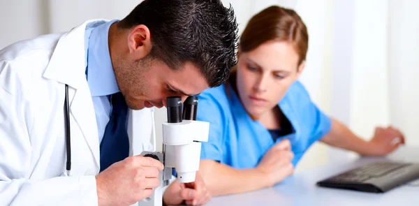 Yakışıklı profesyonel tıbbi bir mikroskop kullanarak — Stok fotoğraf