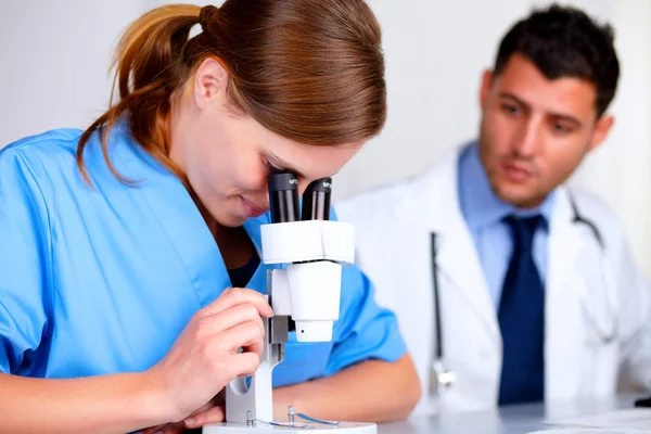 Pretty caucasian doctor girl using a microscope — Stock Photo, Image