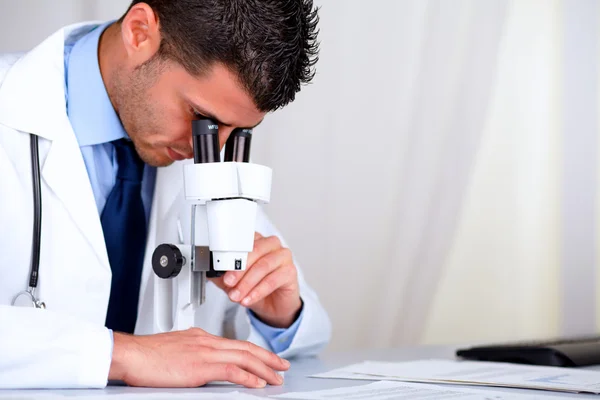 Jeune médecin attrayant travaillant avec un microscope — Photo