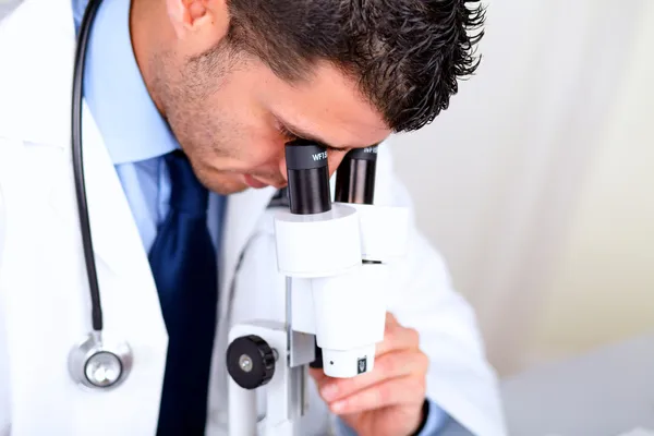 Médico latino atraente usando um microscópio — Fotografia de Stock