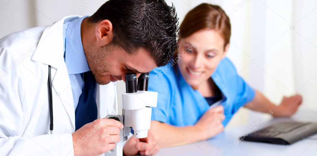 Handsome medical doctor using a microscope