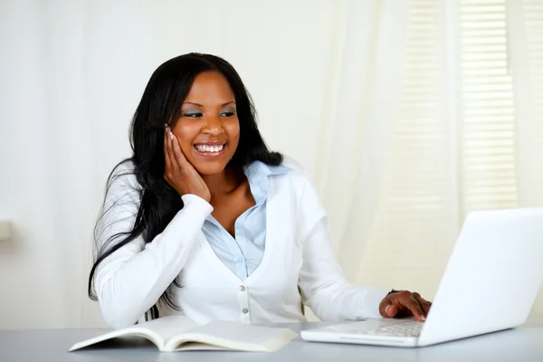 Mujer estudiante encantadora sonriendo y mirando a la computadora portátil —  Fotos de Stock