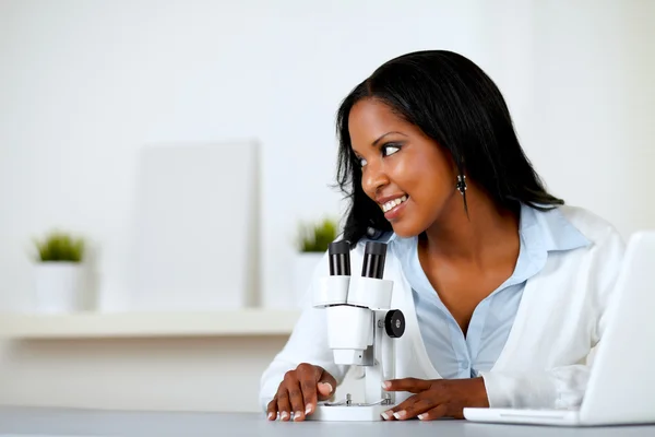 Jovem encantadora usando um microscópio — Fotografia de Stock