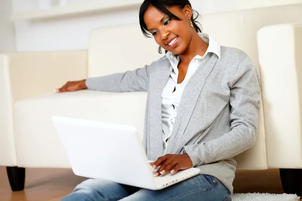 Härlig ung kvinna ler och ser till laptop — Stockfoto