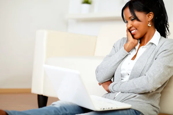 Charming young woman smiling and looking to laptop — Stock Photo, Image