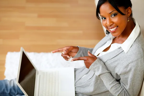 Ung kvinna ler på dig och pekar hennes laptop — Stockfoto