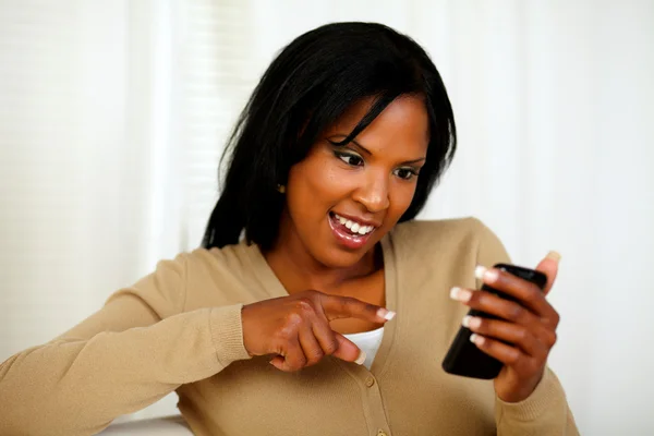 Женщина, указывающая и читающая сообщение по мобильному телефону — стоковое фото