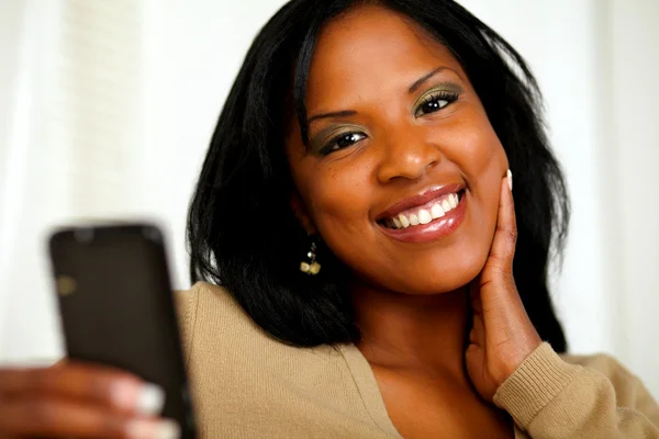 Jovem mulher sorrindo para você enquanto envia uma mensagem — Fotografia de Stock