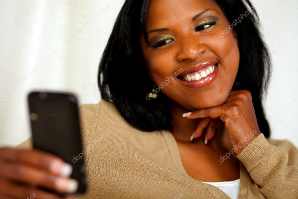 Smiling female sending a message by the cellphone