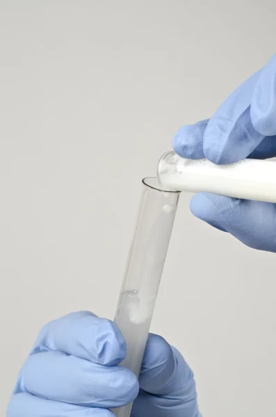 Liquid pouring from one testing tube to another — Stock Photo, Image
