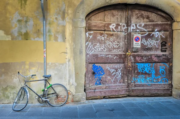 Bicicleta quebrada velha pela porta texturizada de madeira desgastada velha — Fotografia de Stock