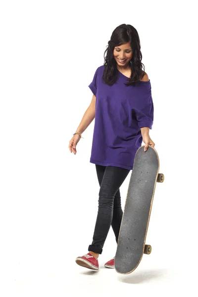 Gelukkig jong meisje lopen met skateboard tegen geïsoleerde achtergrond — Stockfoto