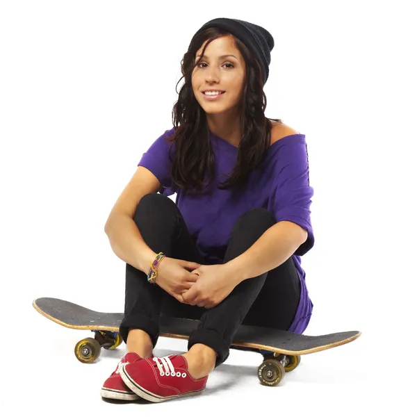 Молодая счастливая женщина сидит на скейтборде снова изолированный фон — стоковое фото
