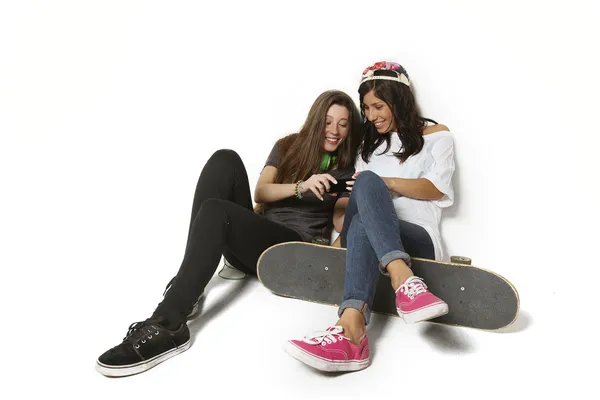 Dois jovens amigos skate menina olhando para fotos no telefonema isolado sobre fundo branco . — Fotografia de Stock