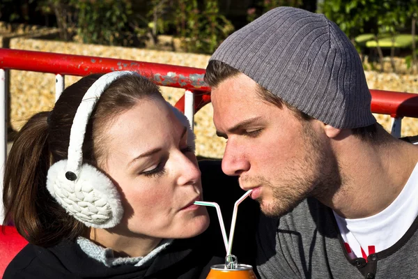 Paar trinkt Saft aus Dose mit zwei Strohhalmen — Stockfoto