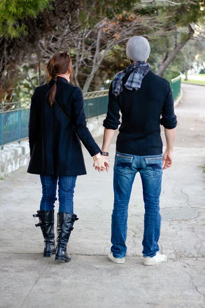 Junges Paar geht Händchen haltend in einem Park spazieren — Stockfoto