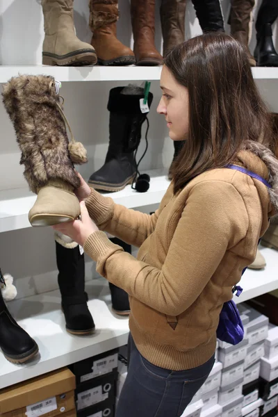 Μια νεαρή γυναίκα μελαχρινή ψώνια για μπότες — Φωτογραφία Αρχείου