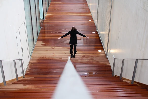 Giovane donna in piedi con le mani divaricate su un pavimento di legno — Foto Stock