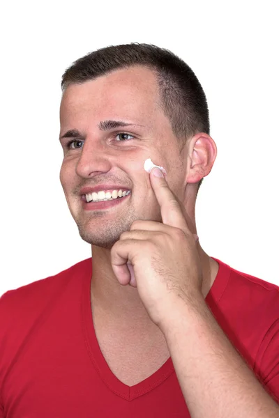 Молодой белый мужчина с кремом-увлажнителем на лице — стоковое фото