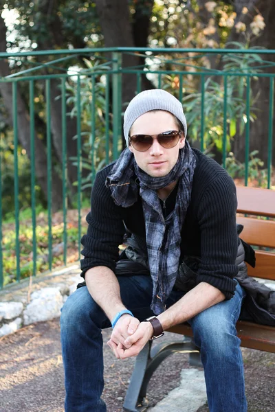 Młody człowiek stylowy, siedząc na ławce — Zdjęcie stockowe