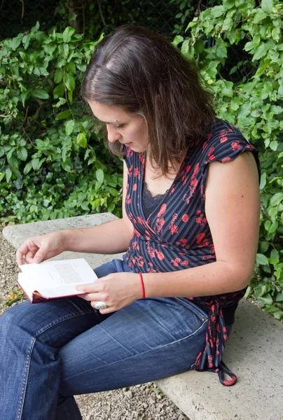 Young woman reading on a bench — Stock Photo, Image