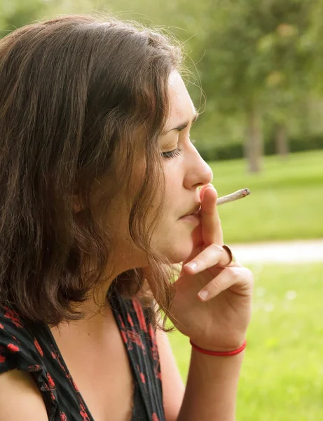 Nainen polttaa käärittyä savuketta — kuvapankkivalokuva