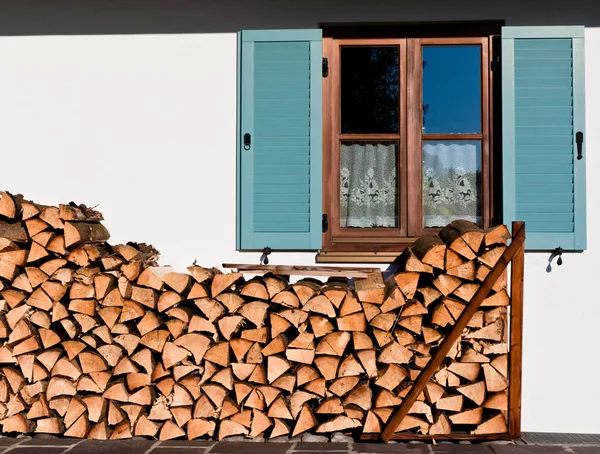 stock image Stack of logs in front of the window