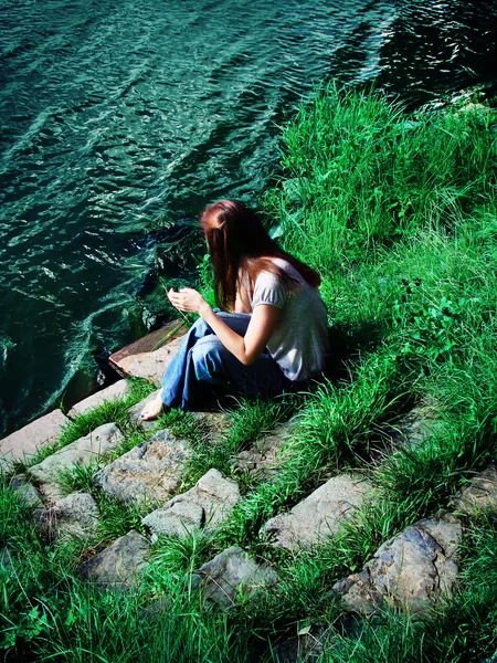 stock image Young woman sitting on the riverbank