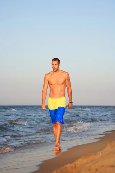 Portret van een jonge man lopen door de zee — Stockfoto