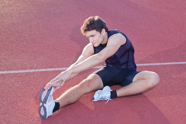 Atleta estiramientos después de correr en el estadio. — Foto de Stock