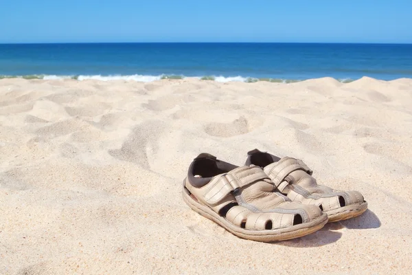 Sandalen am Strand in der Nähe von Meer. — Stockfoto