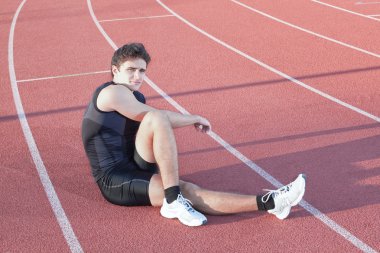 A young athlete makes stretch. Against the background the treadm clipart