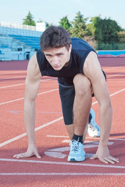 Mladý sportovec začne s nízkou počáteční. proti backg — Stock fotografie