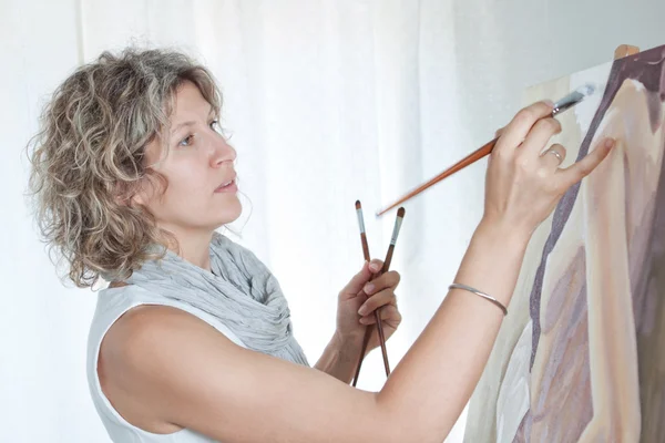 Kvinnlig konstnär måla en bild. mot bakgrund av stu — Stockfoto