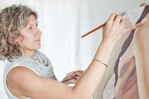 A artista pinta um quadro das escovas. contra o backgrou — Fotografia de Stock