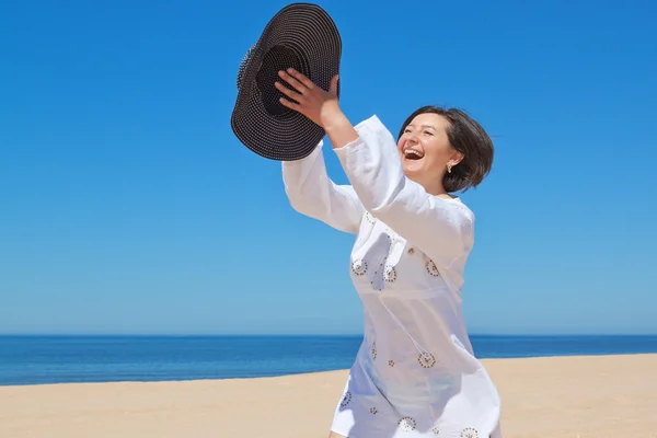 Дівчина на пляжі грає зі своїм капелюхом . — стокове фото