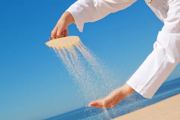 A girl pours sand out of shells on hand. Against the background — Stock Photo, Image