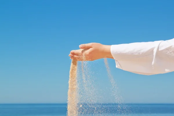 Meisje giet zand uit zijn handen. tegen de achtergrond van de oc — Stockfoto