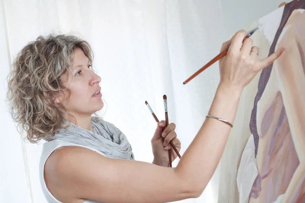 Woman artist draws a portrait of a woman. In the studio.